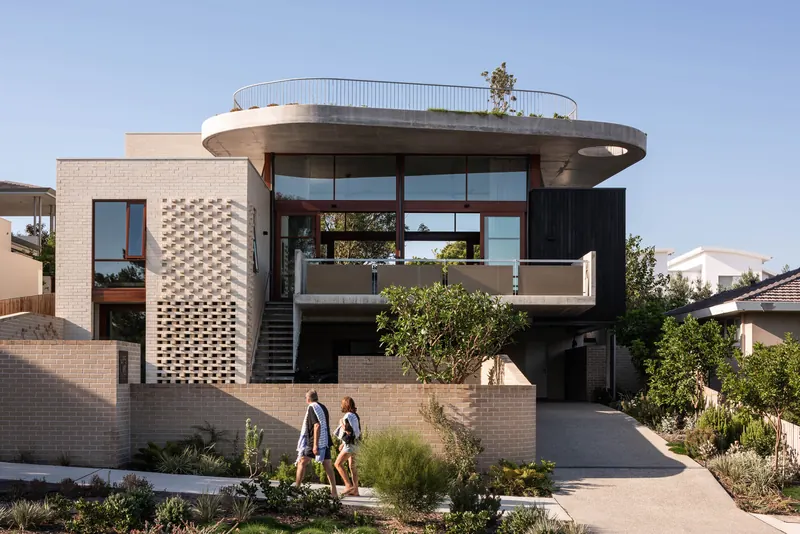 Three-level home with curved balcony and breeze-block tower