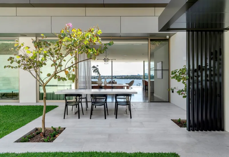 Courtyard dining under a tree with river views beyond